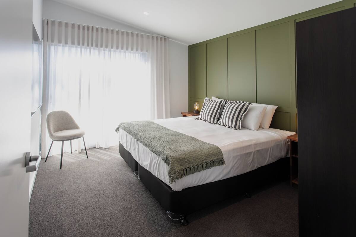 Une chambre à coucher moderne avec un lit, une chaise et une table de chevet.