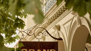 Placa com a inscrição 'Arka Valley Grand', arquitetura clássica e uma varanda.