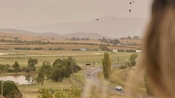 A view of a rural landscape with a road, fields, and a few buildings.
