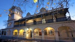 Um edifício histórico com varanda e arcos, com área de estar ao ar livre e uma placa.