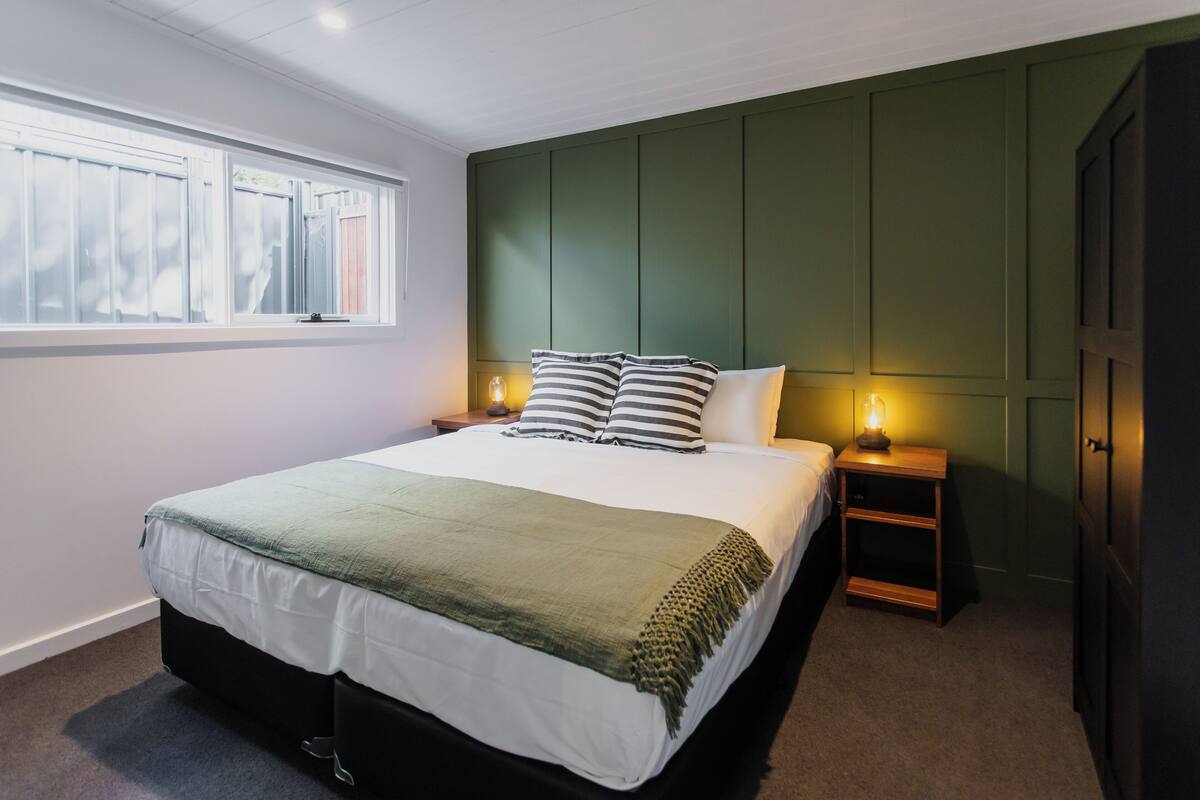 Une chambre à coucher avec un grand lit, une fenêtre et une table de chevet avec une lampe.