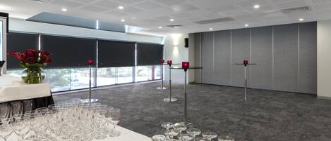 A conference room with a long table set for a meeting, equipped with a projector and a screen.