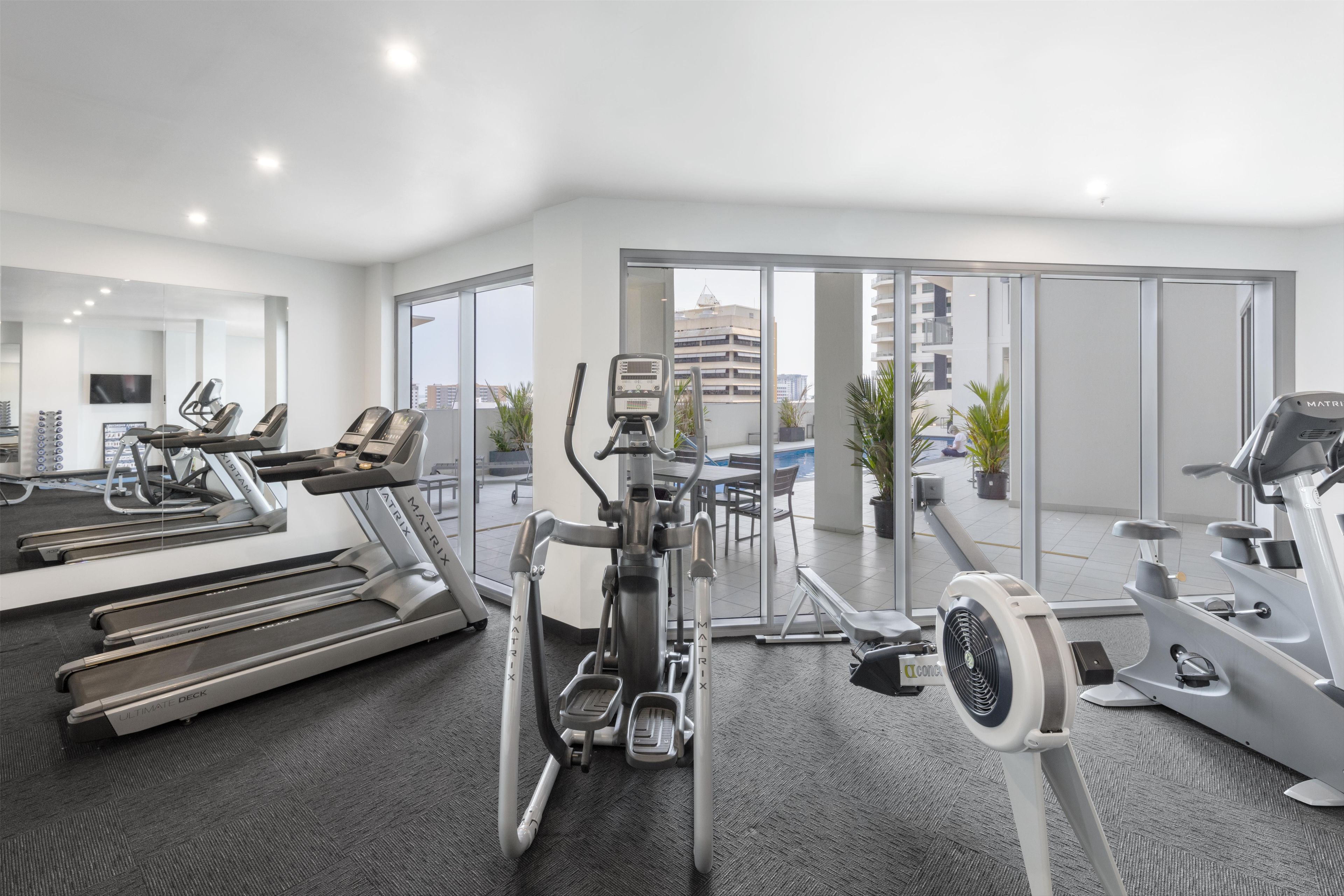 A modern gym with treadmills, elliptical machines, and a stationary bike.