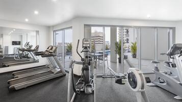 Un gimnasio moderno con cintas de correr, elípticas y una bicicleta estática.