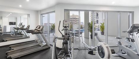 A modern gym with treadmills, elliptical machines, and a stationary bike.