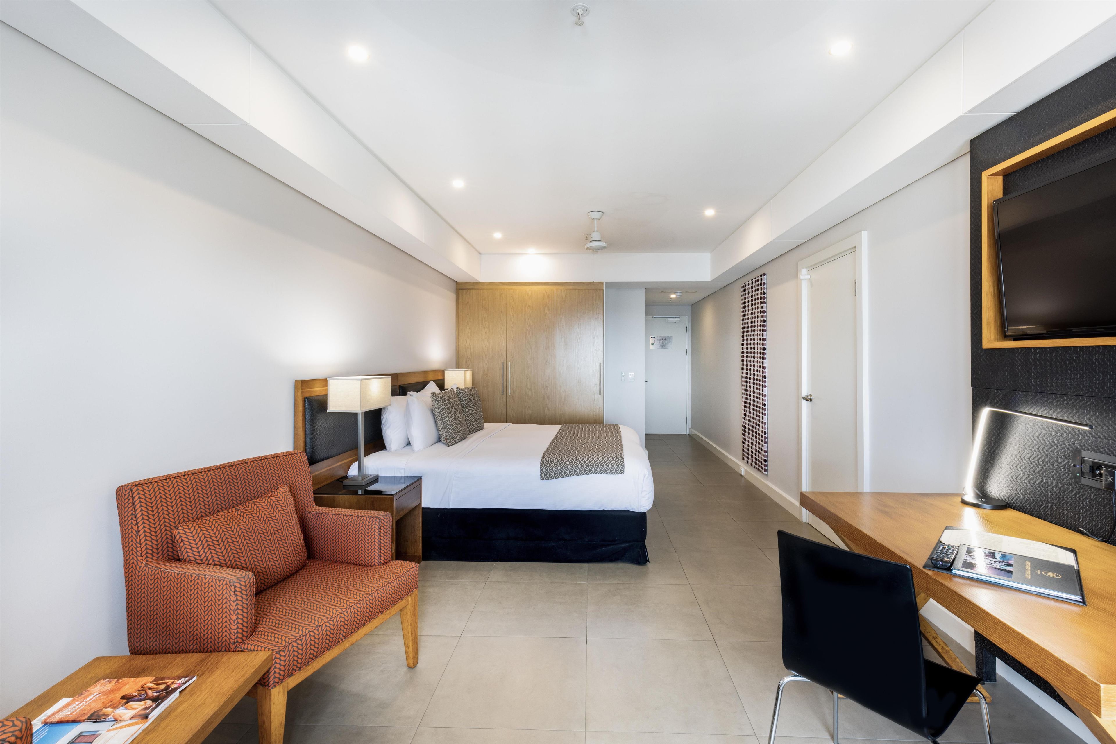 Une chambre d’hôtel avec un lit, un bureau, une chaise et un téléviseur.