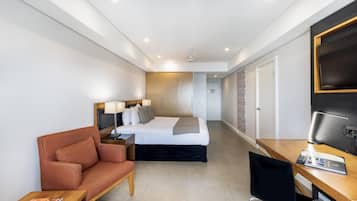 Une chambre d’hôtel avec un lit, un bureau, une chaise et un téléviseur.