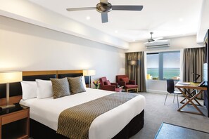 A hotel room with a large bed, a desk, a chair, and a view of the sea. - Oaks Darwin Elan Hotel (Darwin)