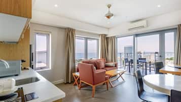 Et moderne hotelværelse med balkon, sofaarrangement, spisebord og tekøkken.