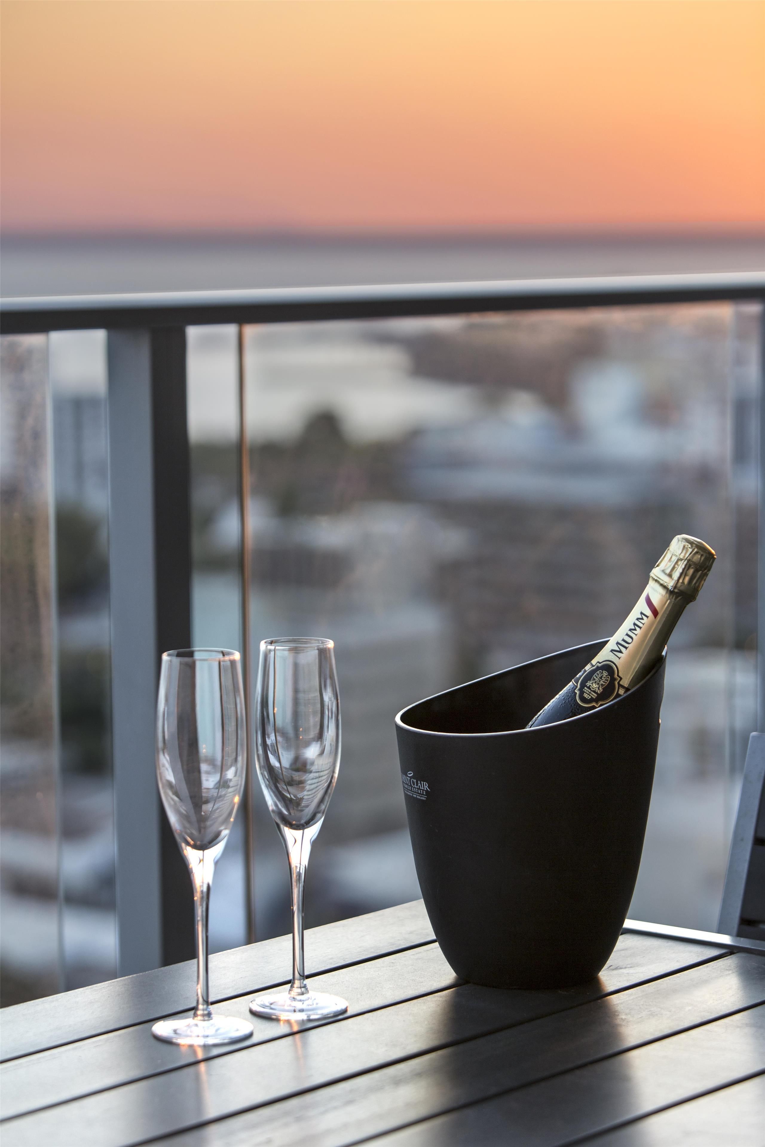 Ett bord med två tomma vinglas och en svart hink som innehåller en flaska champagne.