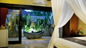 A bedroom with a bed, a large window, and a view of a garden. - Hidden Paradise Cottages (Karangasem)