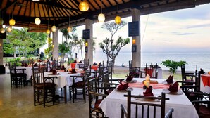 A restaurant with tables set for dining, overlooking a body of water. - Hidden Paradise Cottages (Karangasem)
