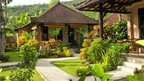 A traditional building with a tiled roof, surrounded by lush tropical gardens and a clear sky. - Hidden Paradise Cottages (Karangasem)