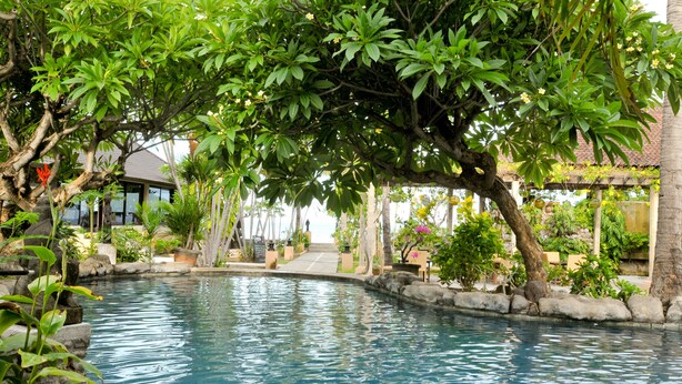 A serene pool area with a stone border, lush greenery, and a clear blue pool. - Hidden Paradise Cottages (Karangasem)