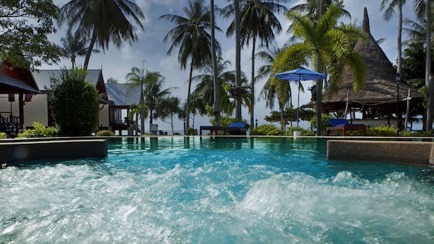 Una piscina al aire libre, sombrillas, sillones reclinables de piscina