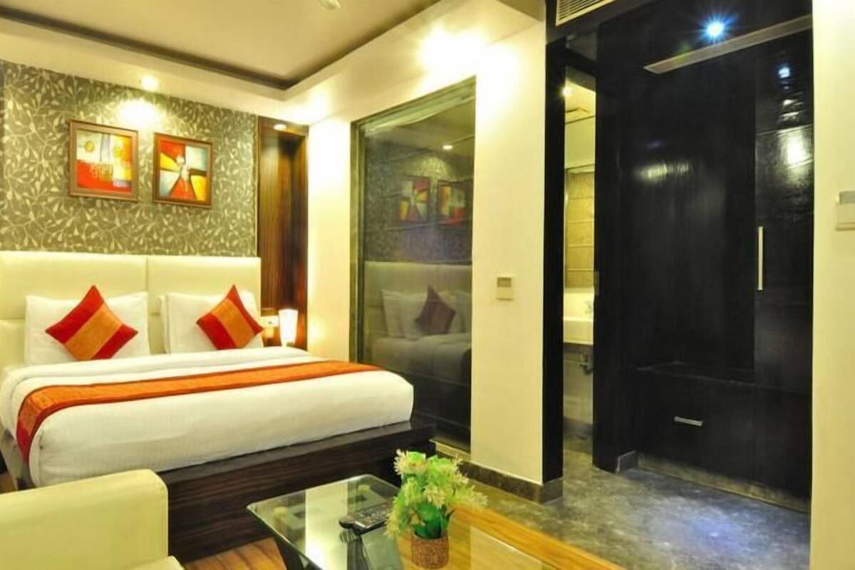 Una habitación de hotel con una cama, una mesa de centro de vidrio y una puerta que da a un baño.