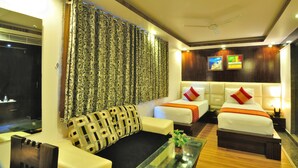 Una habitación de hotel con dos camas, un sofá, una mesa de centro y un televisor.