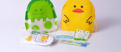 Two plush toys, one green and one yellow, with a small package and a toy train set in front.