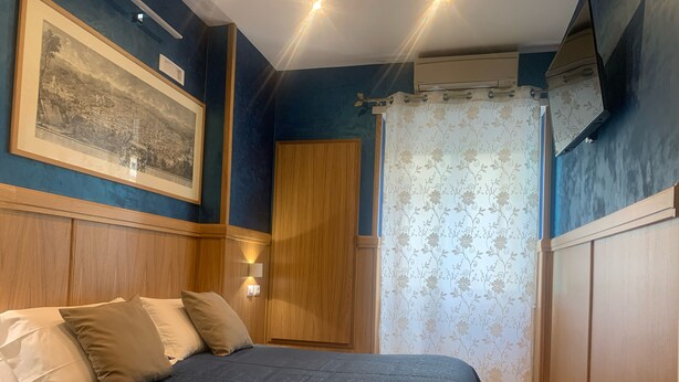 A bedroom with a bed, wooden headboard, wall-mounted air conditioning unit, and a framed picture. - B&B A Casa di Barbara (Rome)