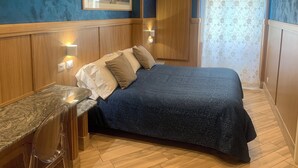A bedroom with a bed, a wooden wardrobe, a framed picture on the wall, and a bathroom with a curtain. - B&B A Casa di Barbara (Rome)