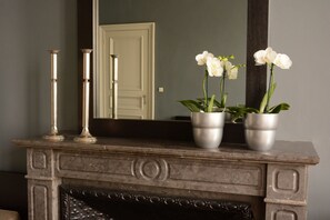 A fireplace with three potted white orchids on the mantel. - Dusk Till Dawn (Mechelen)