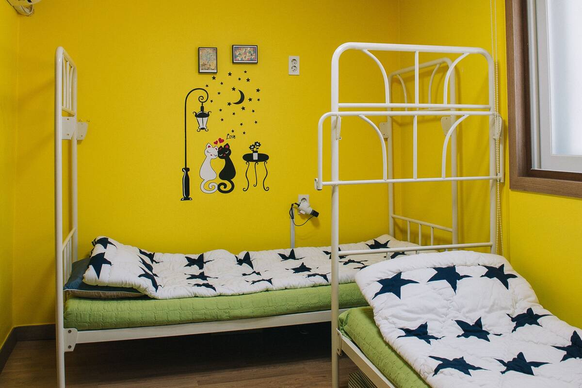 A room with two bunk beds, a wooden ceiling, a window, and a wall with a star pattern.