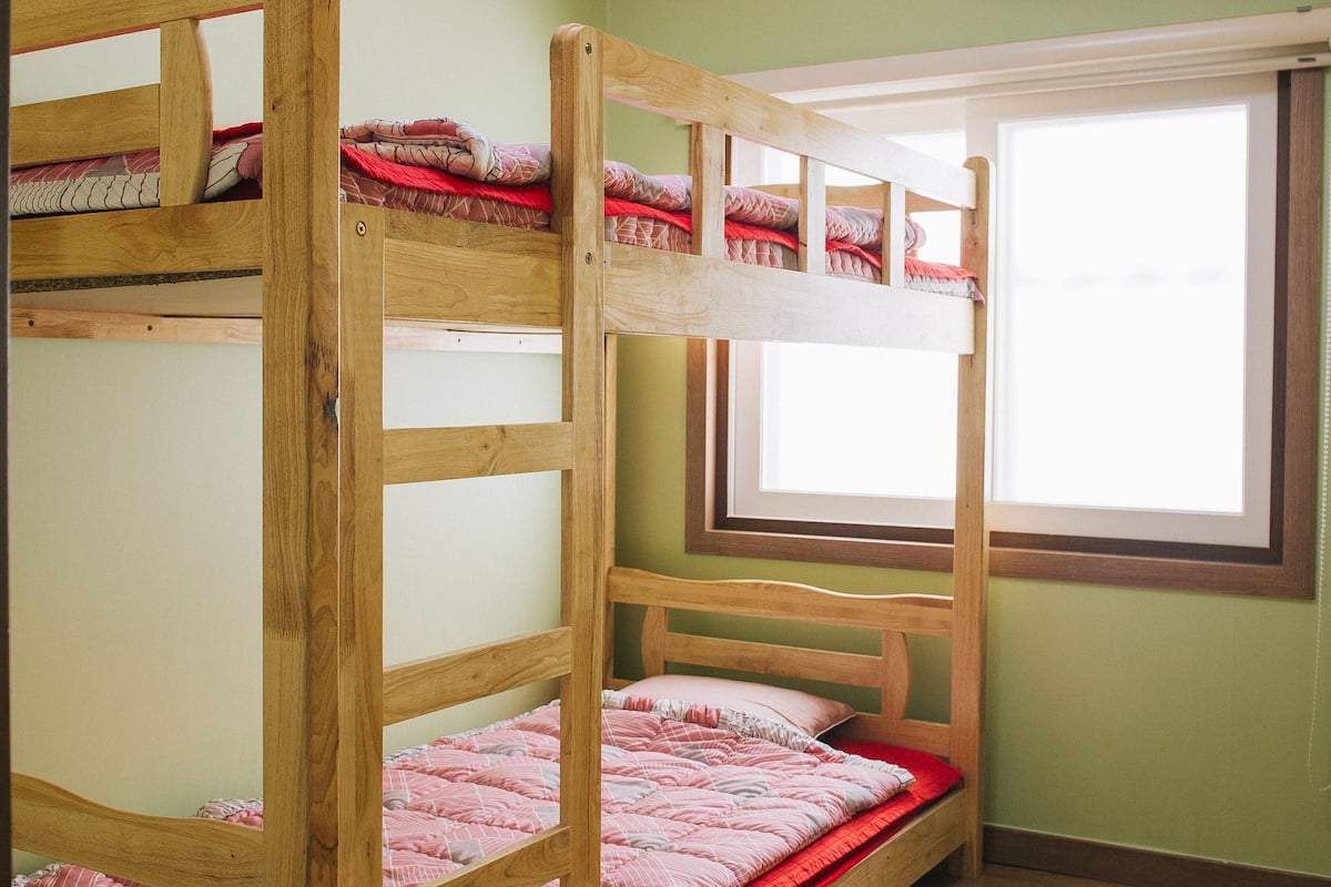 A bunk bed room with a skylight, an air conditioning unit, and a window.