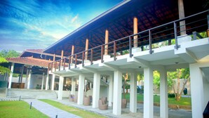 A covered outdoor area with a series of columns supporting a roof, a pathway, and seating areas. - Ranna 212 (Kahandamodara)