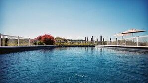 A swimming pool with a white fence, a red flower bush, and a clear blue sky. - Relais des Vigiers (Monestier)