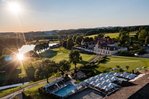 Un campo de golf con un club de campo, piscina y aparcamiento.