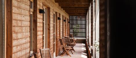 A covered outdoor seating area with wooden chairs and a tiled floor.