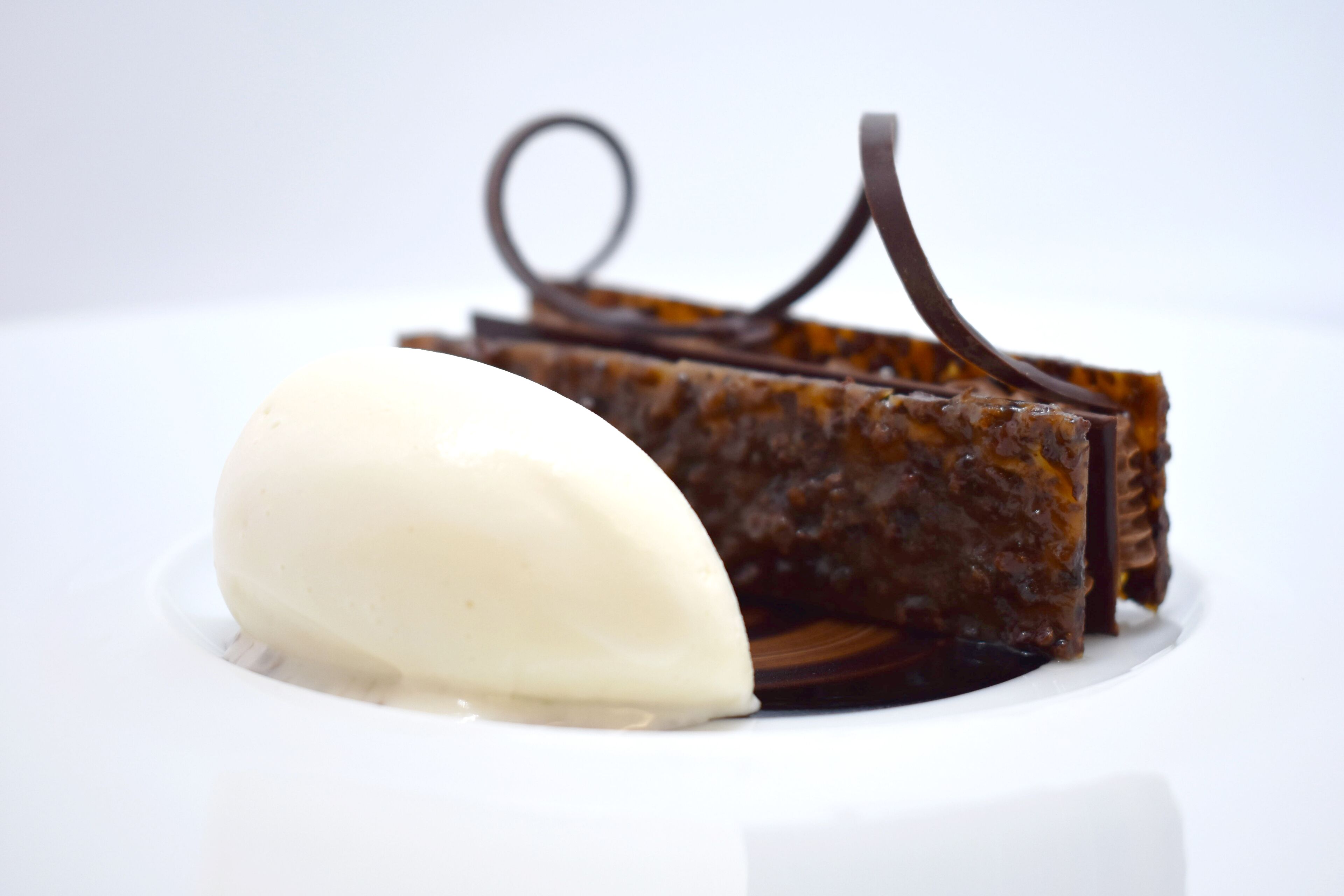 A dessert with a scoop of ice cream and chocolate pieces on a white plate.