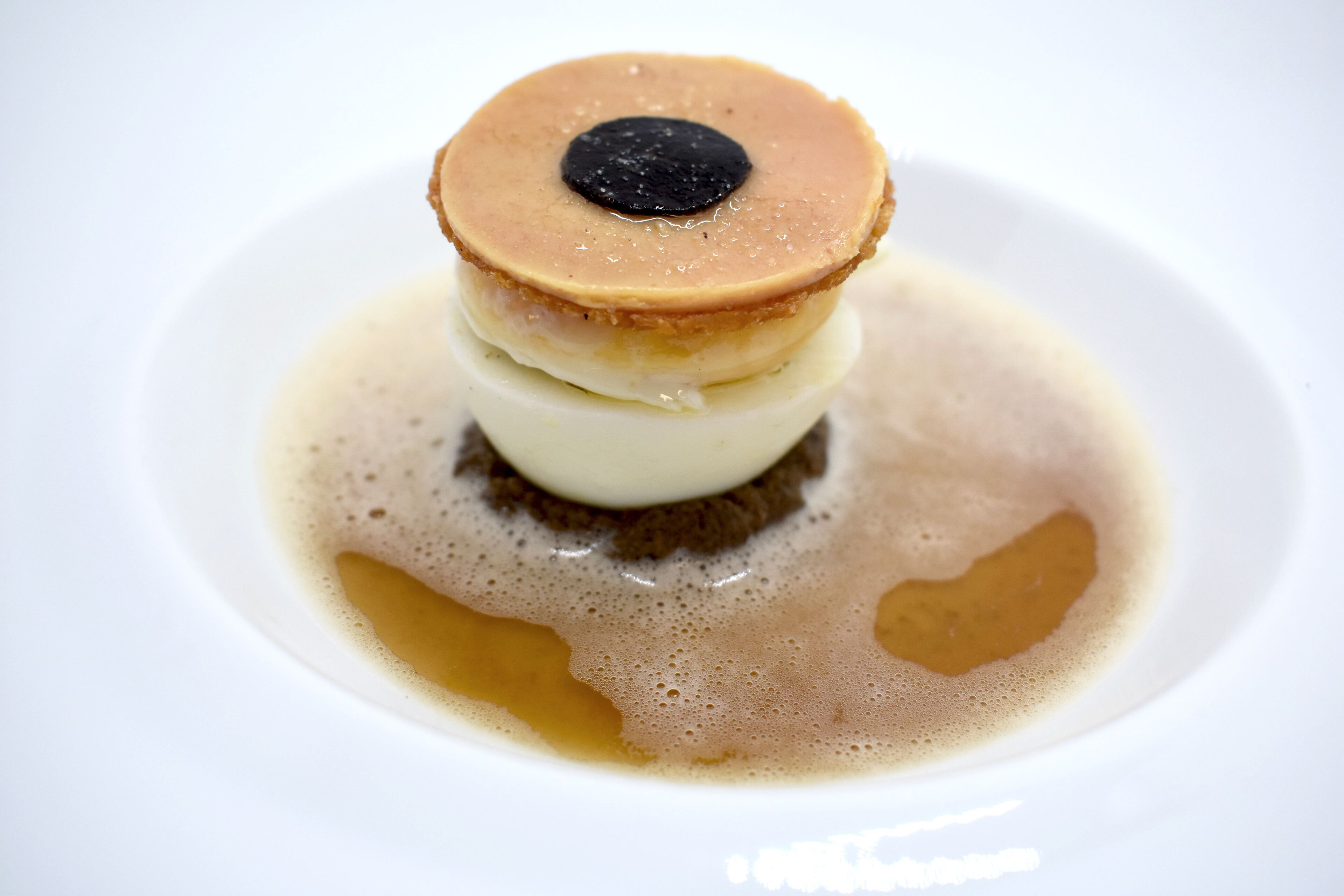 Un dessert avec une croûte caramélisée et un cœur coulant, servi dans une assiette blanche.