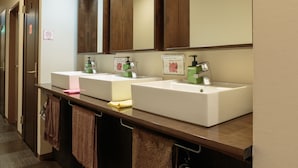 A hotel bathroom with two sinks, wooden cabinets, and a mirror.