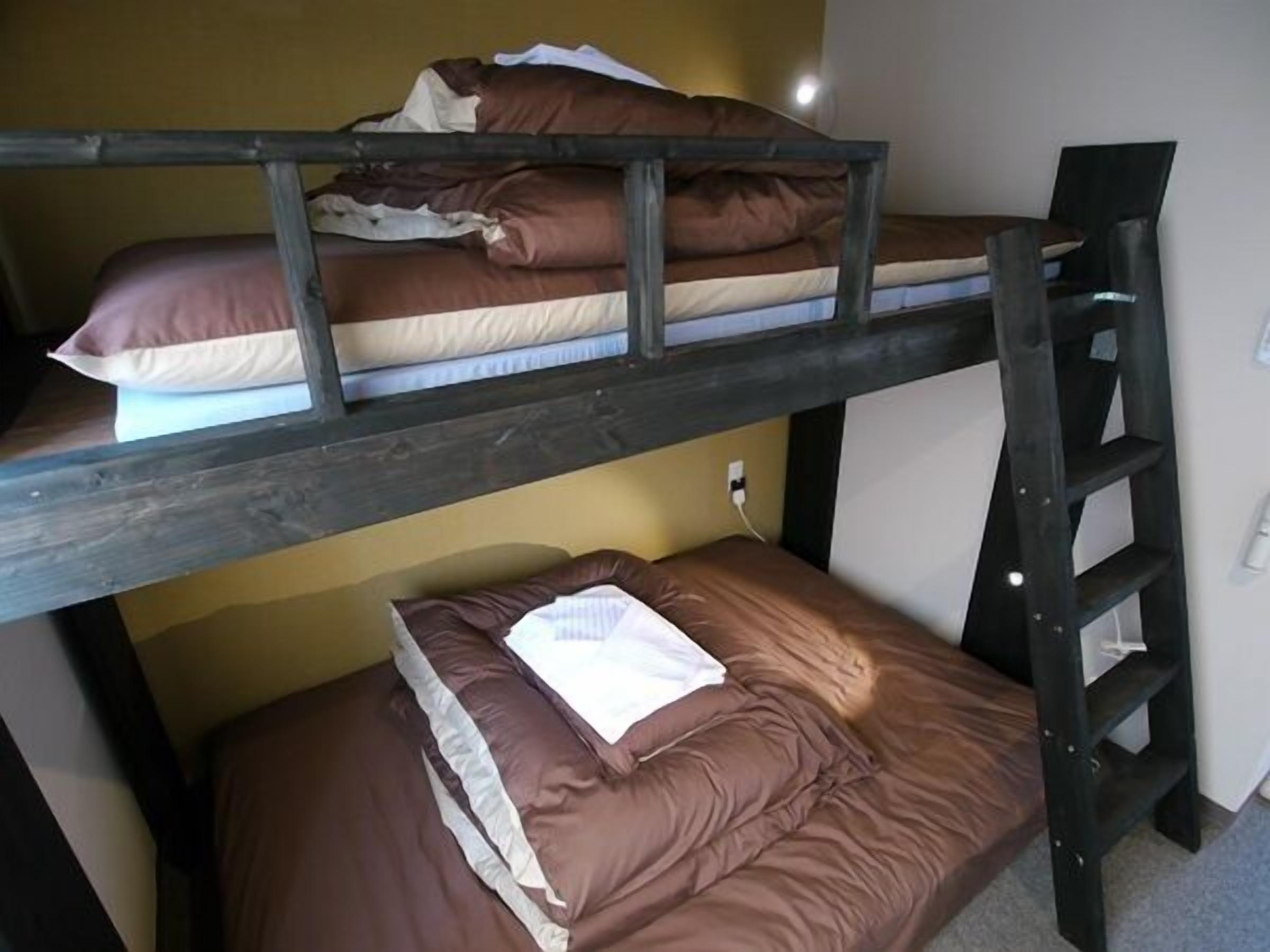 Un lit superposé avec une échelle, un oreiller et une couverture sur le lit du bas.