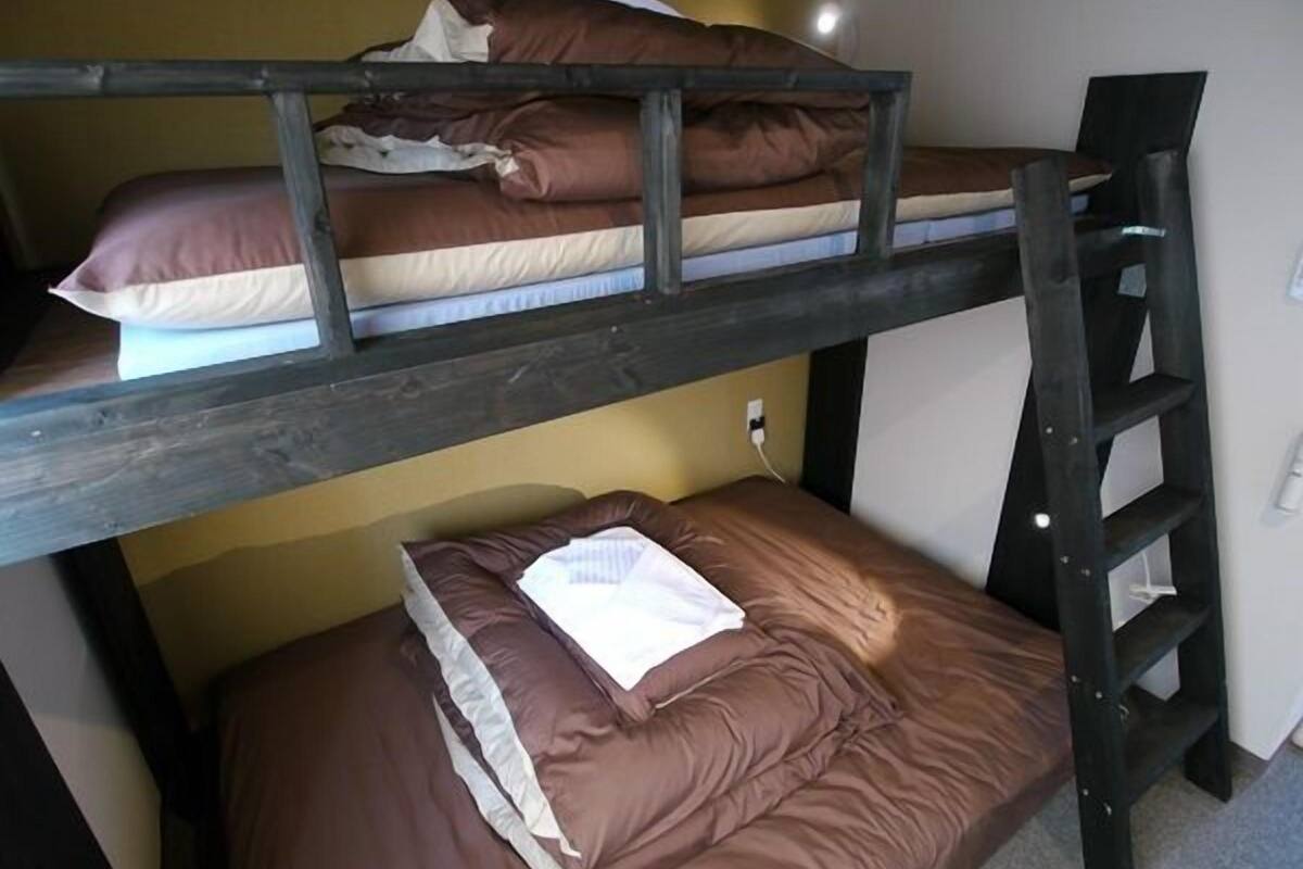 A bunk bed with a ladder, a pillow, and a blanket on the lower bunk.