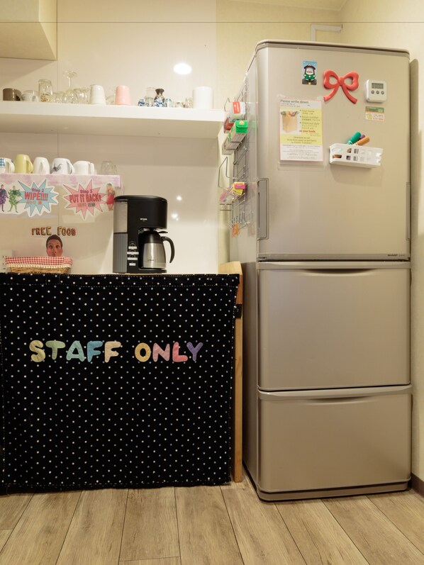 A kitchen with a refrigerator, a coffee maker, and a 'Free Food' sign.