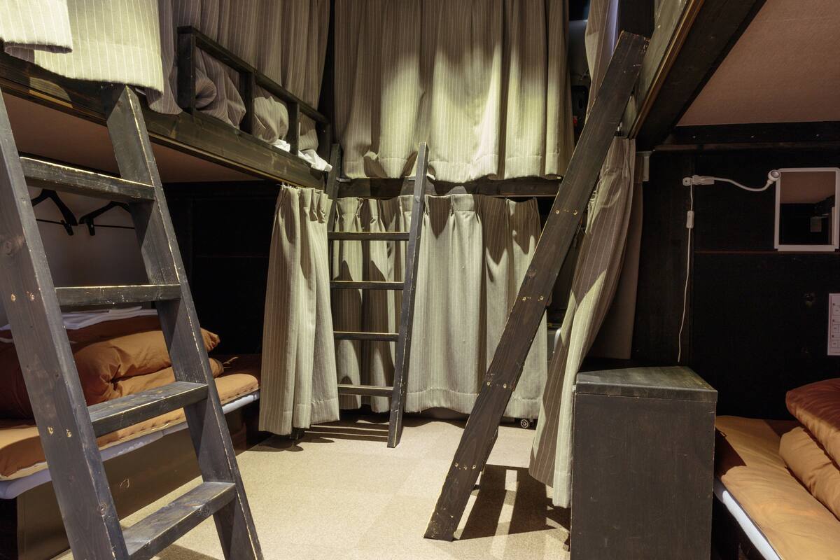 A compact room with bunk beds, a ladder, and a small desk.
