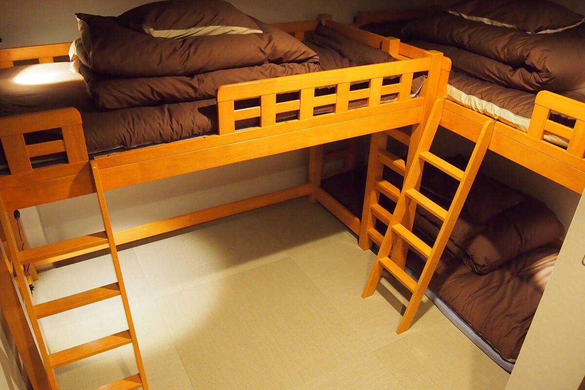A bunk bed with a ladder, a small shelf, and a pillow.