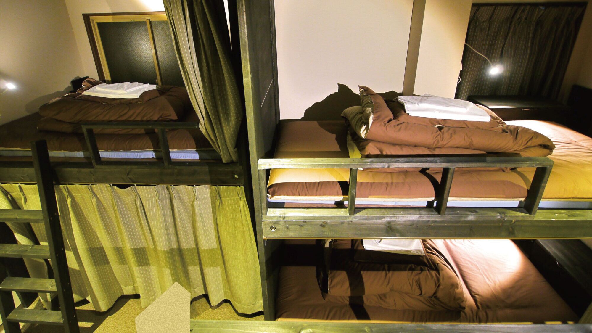 Des lits superposés avec des oreillers et des couvertures, une échelle en bois et un miroir au mur.