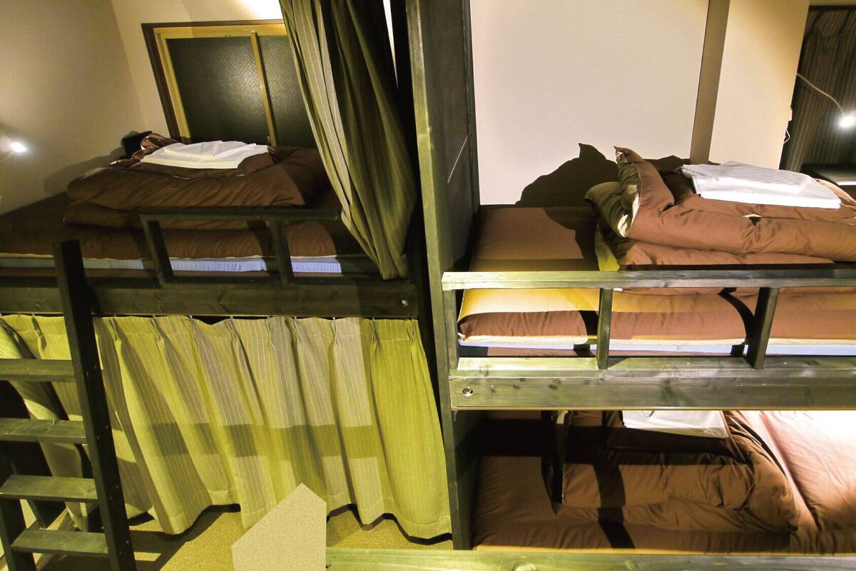 Bunk beds with pillows and blankets, a wooden ladder, and a mirror on the wall.