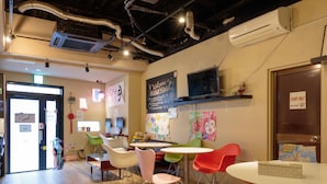 A modern interior with wooden flooring, a variety of colorful chairs, a flat-screen TV, and a chalkboard with welcoming messages.