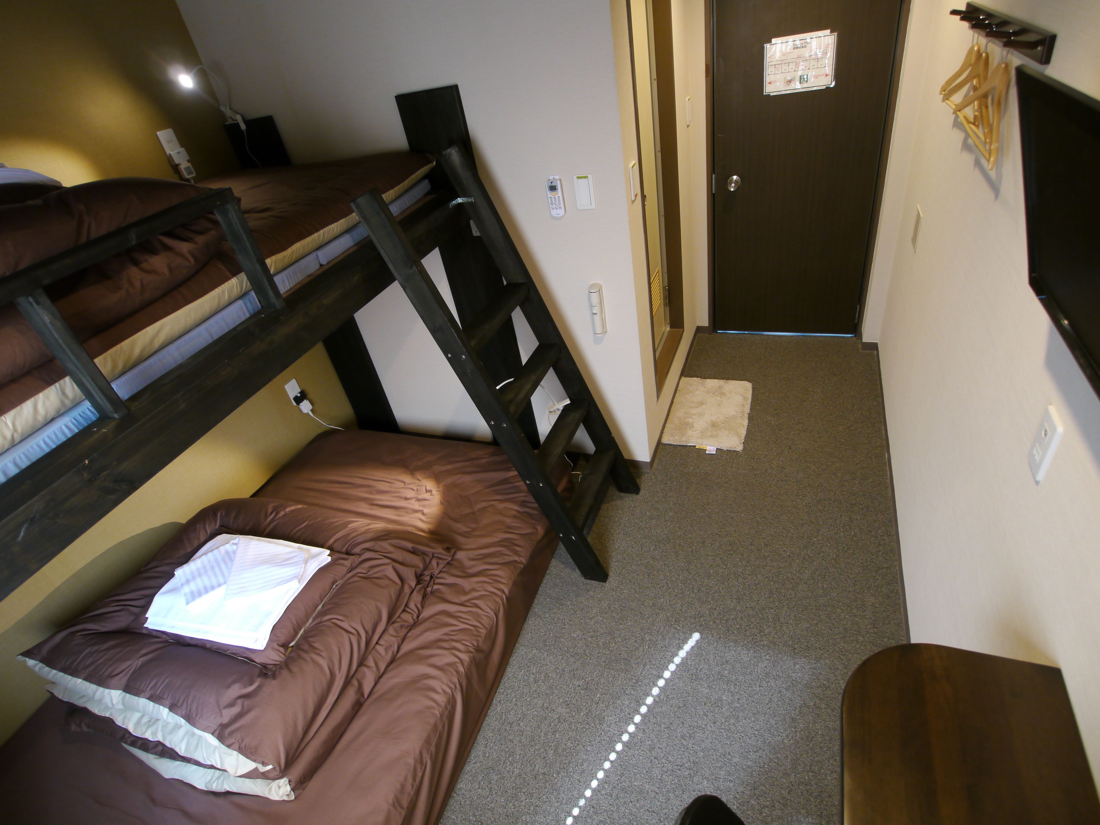 A bunk bed room with a desk and a door.