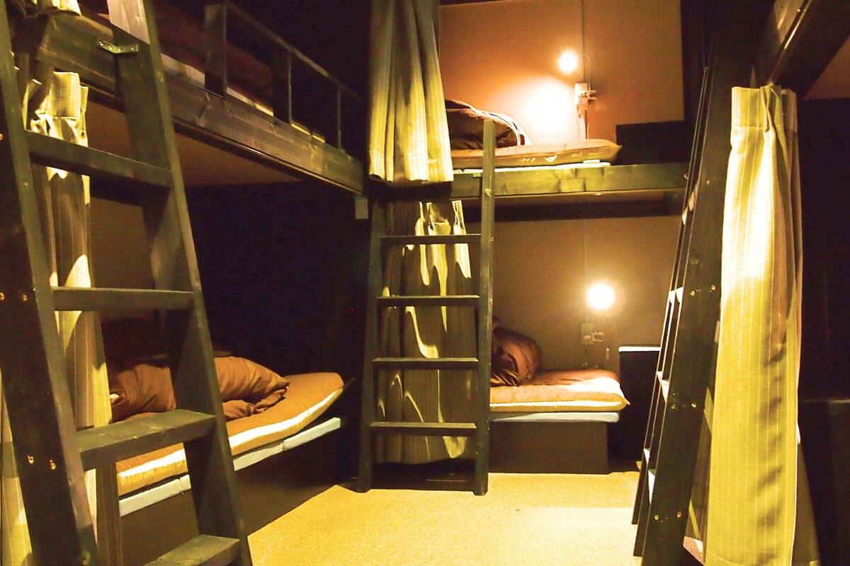 A bunk bed room with a ladder, a desk, and a lamp.