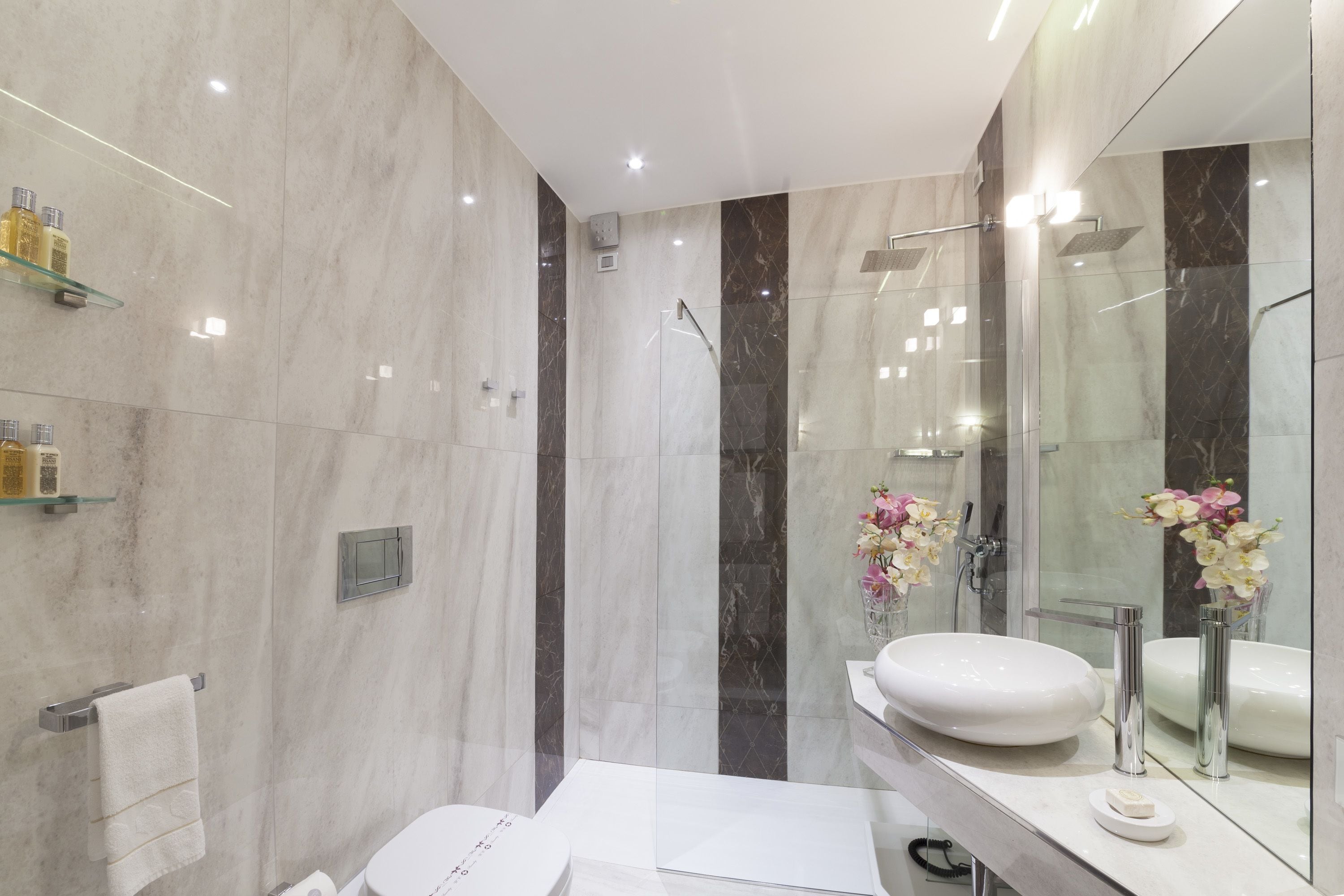 Un baño moderno con cabina de ducha de vidrio, un lavabo blanco y un espejo grande.