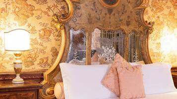 Un dormitorio con una cama grande y decorativa, una mesita de noche con lámpara y un espejo.