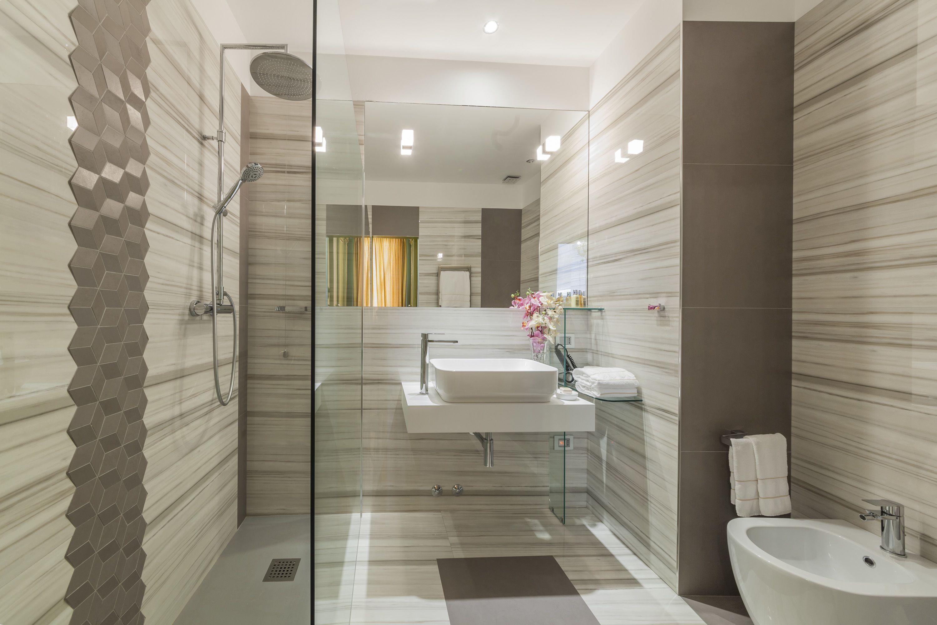 Une salle de bain moderne avec une douche à parois de verre, un lavabo blanc et un bidet.