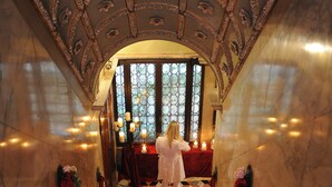 A grand staircase with red carpet leading to a room with a large window and ornate ceiling. - Palazzetto Pisani (Venice)