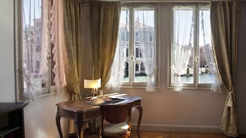 Una habitación con escritorio, silla y vistas a un edificio a través de amplios ventanales.