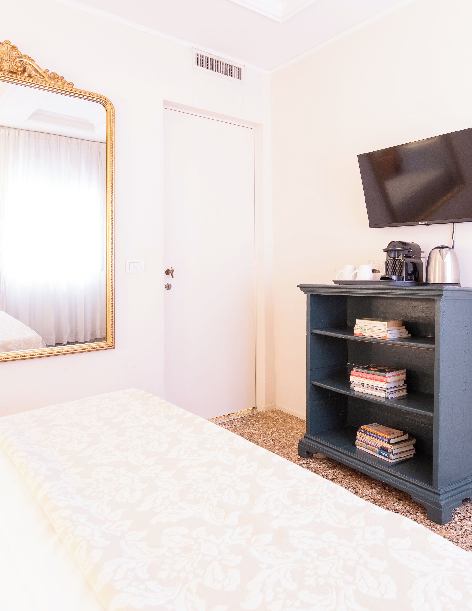 Una habitación de hotel con cama, estantería, televisión y puerta.